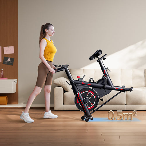 A woman easily rolling a compact exercise bike with built-in wheels in her home, showing its small 0.5 sqm footprint.