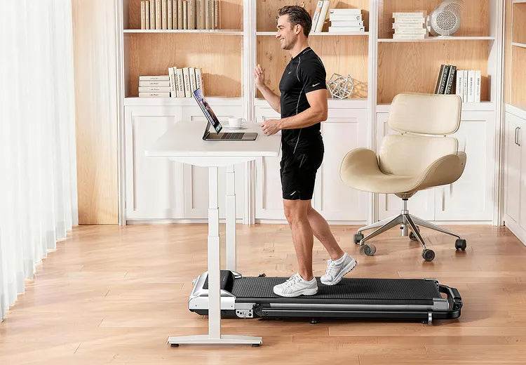 Male adult performing low-impact exercises using TP6 under-desk exerciser at his desk
