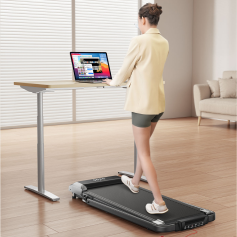 A professional woman walking on a under-desk walking pad while working at her standing desk, effortlessly integrating fitness